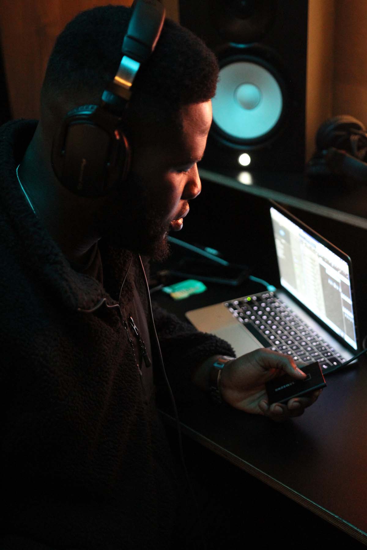 Young man holding Samsung Portable SSD T7 Touch at editing station