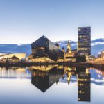 A modern city skyline, Liverpool UK, reflected in water while the sun sets