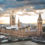 A large building called Big Ben in London with a clock tower and a bridge over a river