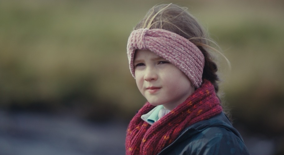 girl with a pink headband and red scarf standing in a field