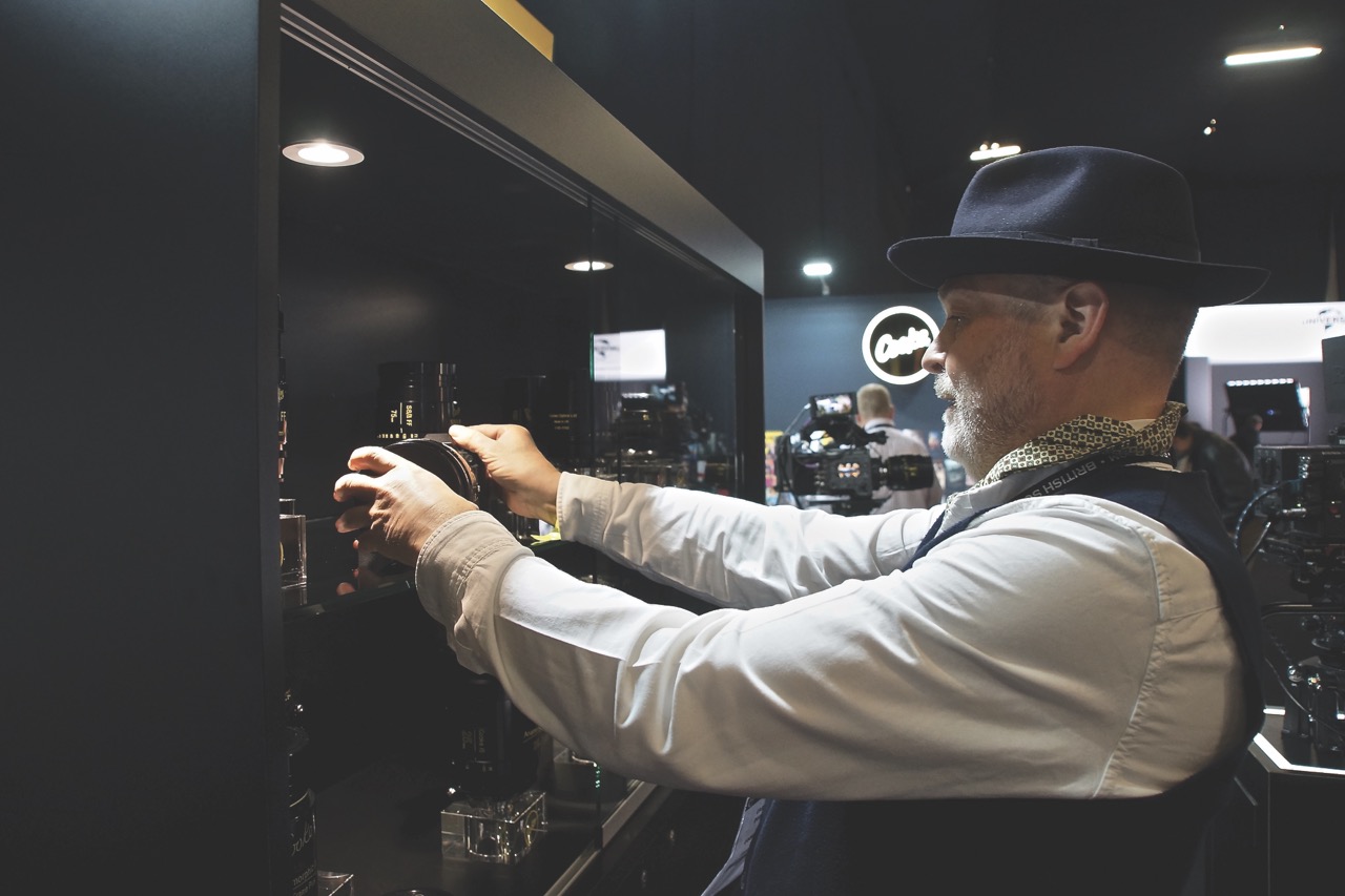 A person wearing a hat taking a camera out of a glass cabinet