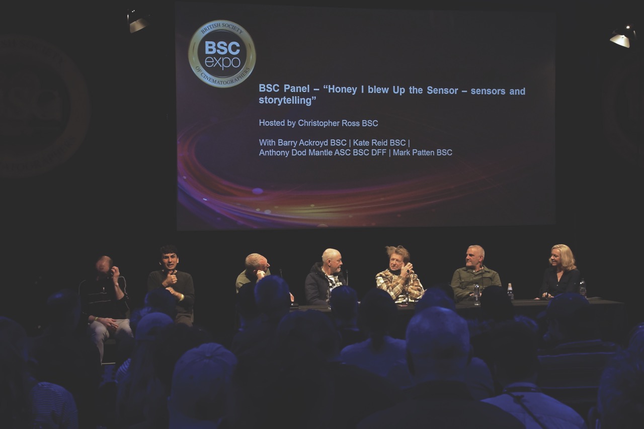 A panel of people sitting on stage in front of a projector scene for BSC Expo. An audience sits in front of the panel