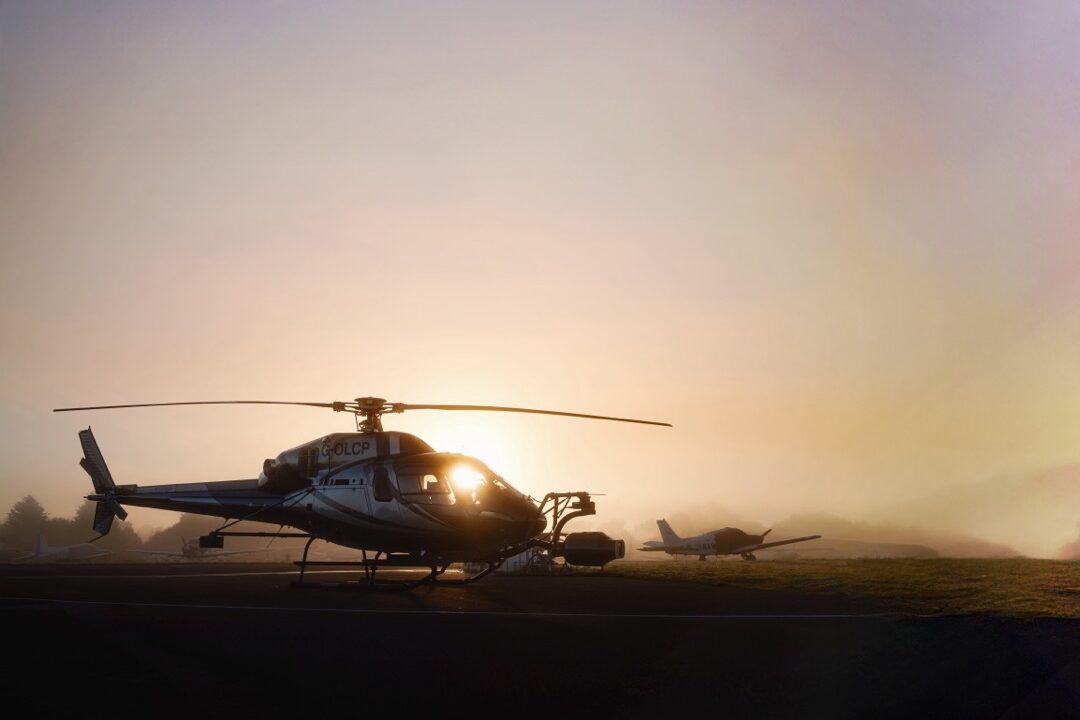 A helicopter in silhouette standing in front of a sunset