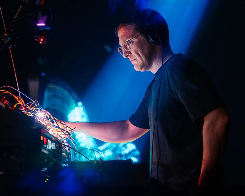 A person with headphones and wires playing music on stage. Image: Genevieve Reeves & Seb Gardner