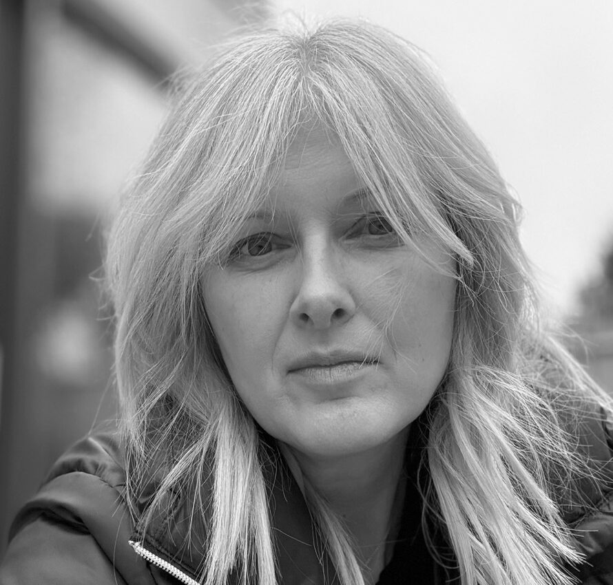 Black-and-white photo of a woman wearing a coat looking at the camera