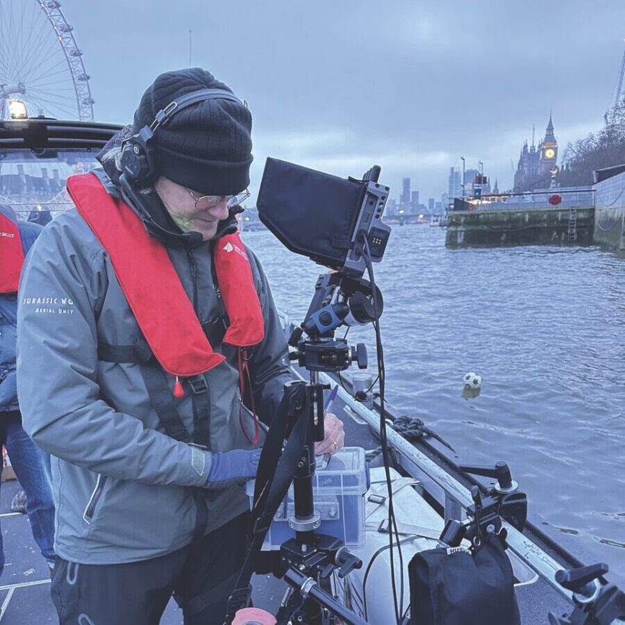 A person standing on a boat in the London Thames with a camera