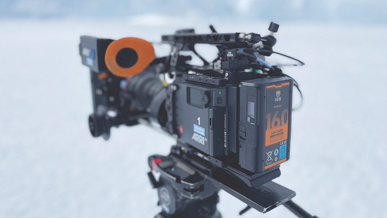 A camera on a mount with a red eye piece. It is placed outside in the snow