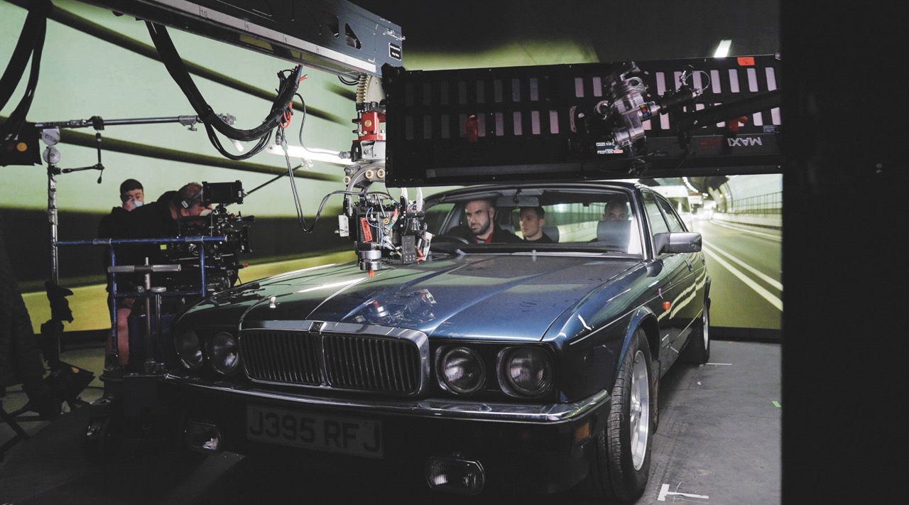 A vintage car in a diling studio with monitors and equipment surrounding it