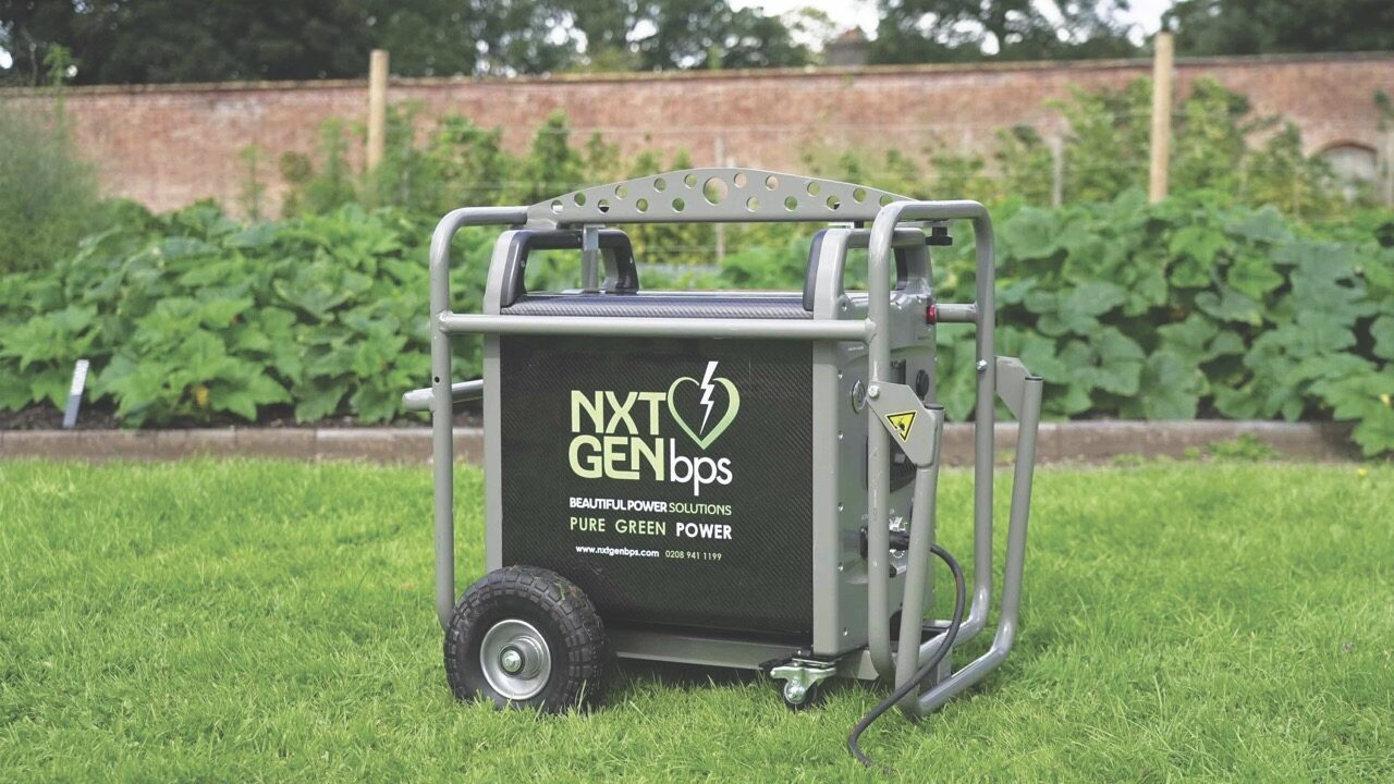 A large metal battery on wheels. It is placed outside on some grass