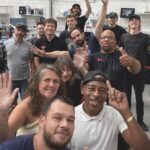 A group taking a selfie. They reach their arms up