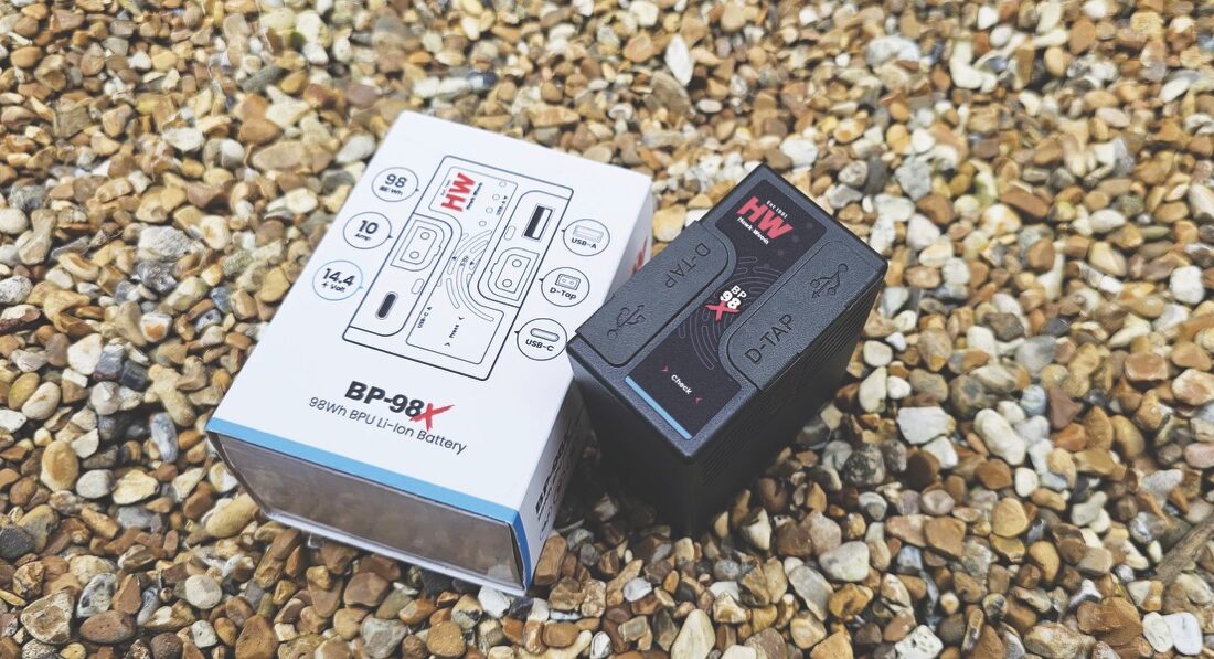 A black battery and a white box laying on gravel