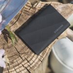 Top view of a hard drive sitting on a wooden stump next to a watering can and flowers