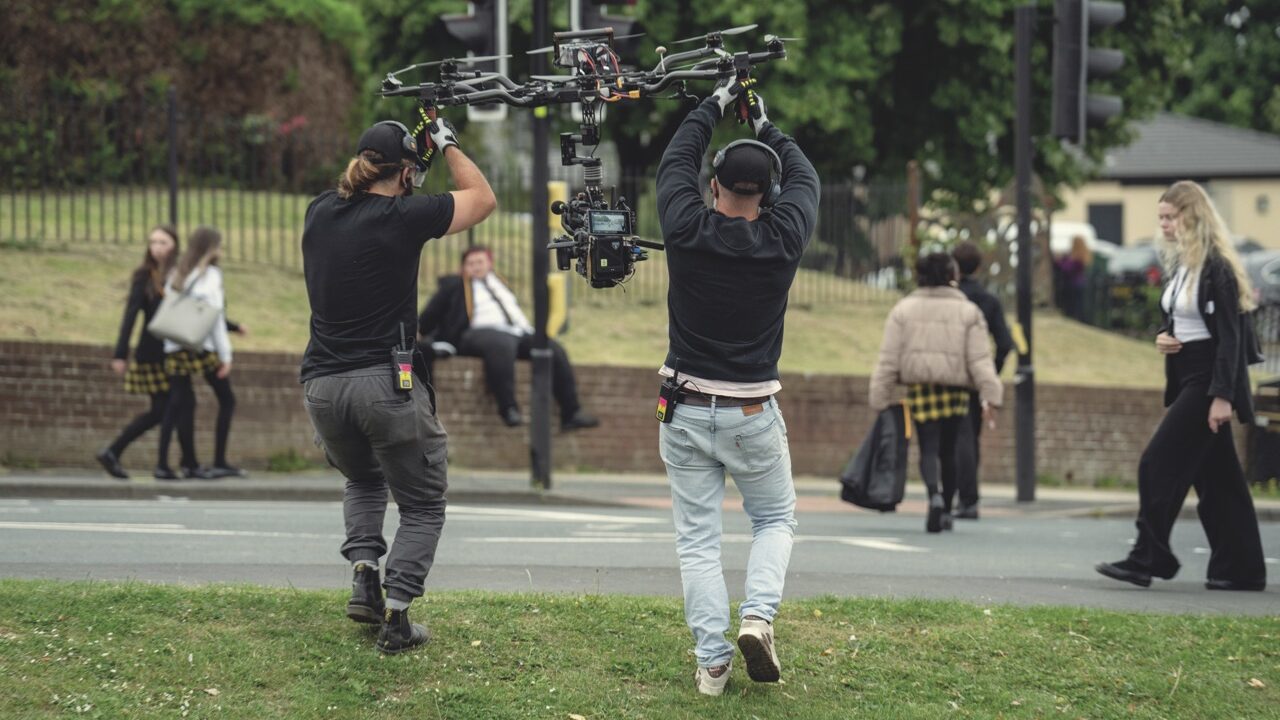 A group of people standing in a field carrying a drone as it begins to fly
