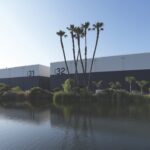 Two cube buildings with numbers on the side sitting next to a body of water. Palm trees grow between the water and the buildings