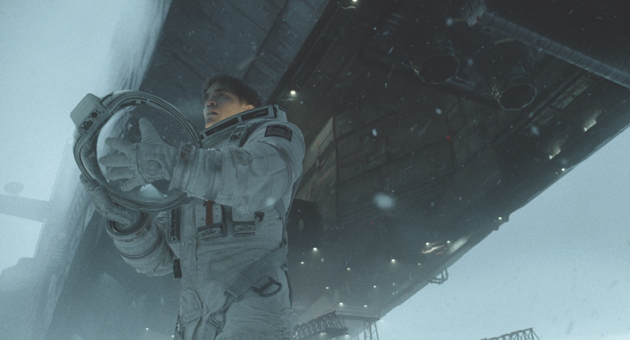 A low shot of a person in a space suit holding a helmet