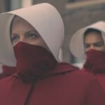 Rows of women wearing red dress and masks and white hats
