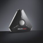 A black triangle device with a white circle centre, against a glowing black background