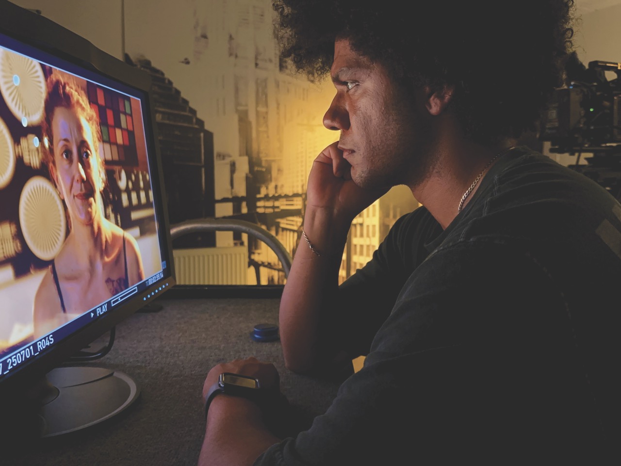 A man sits in a dim room staring intently at a woman on a screen