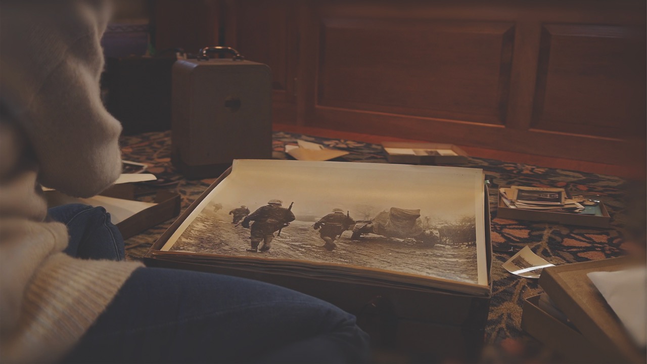 A realistic animation over the shoulder of a person looking at a photo of soldiers going to war