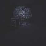 A globe made of lights with an amp and technology placed in front, against a black background