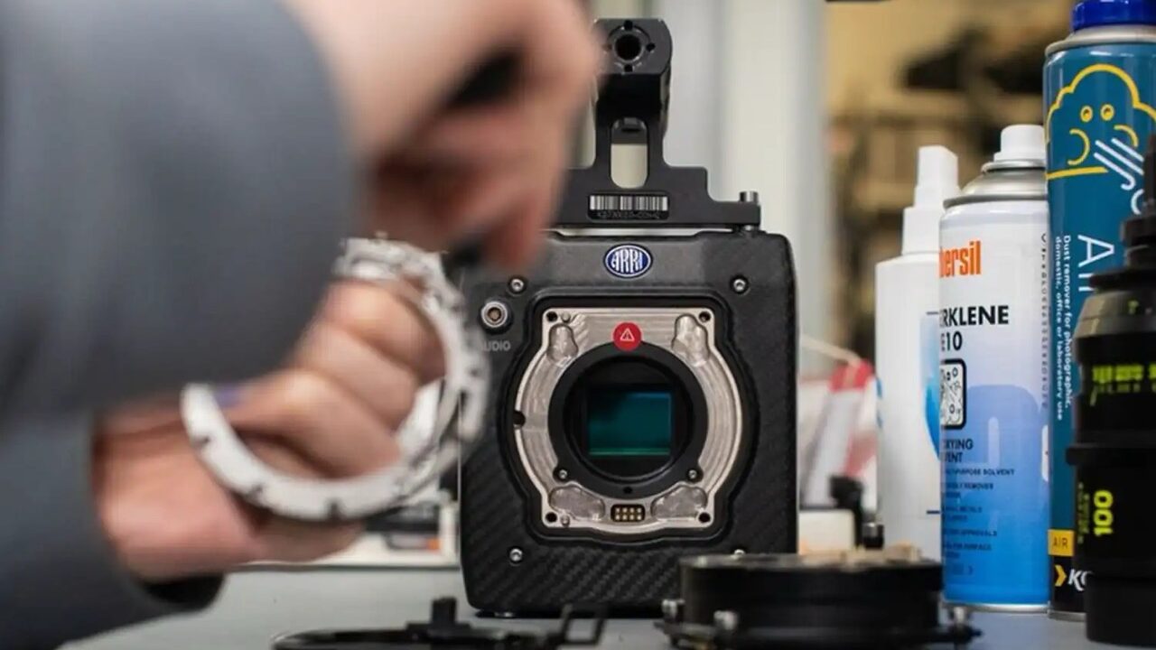 Blurred hands adjust a lens on a camera at a workbench