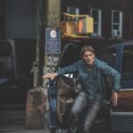 A man in a blue shirt running out of a car in a city