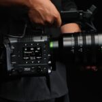 A black filmmaking camera from Fujifilm, sitting on a black sheet and against a black background