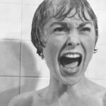 A black and white photo of a woman screaming in a shower