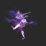 A football player kicking a ball, surrounding by a purple glow, against a black background