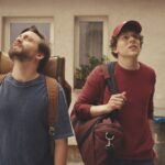 A still from A Real Pain showing two men looking upwards in a city