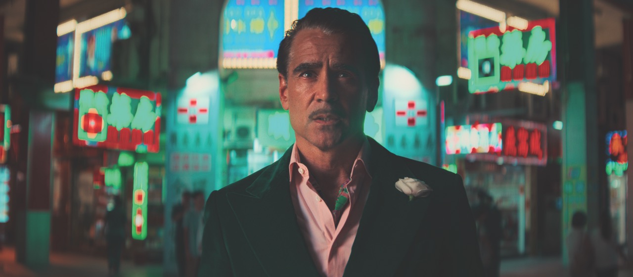 Still from Ballad of a Small Player showing a man with a moustache and wearing a suit standing in a neon city