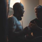 A dimly lit room with two members of a film crew talking