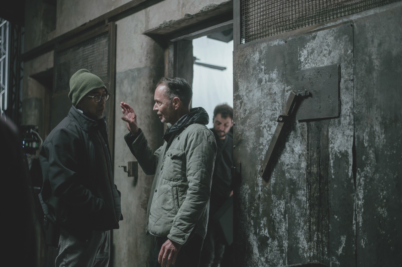 Two handheld cameras on Easyrigs were used to capture scenes in the prison cell A still from Kiss of the Spider Woman showing a grey military setting with men standing near a wall