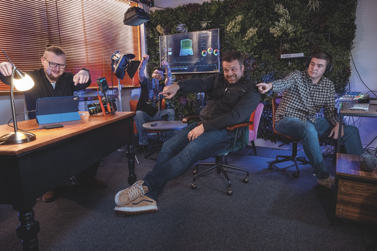 A group of people working in a modern office and pointing at a small black Samsung hard drive on a wooden desk