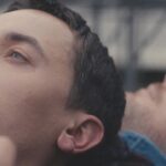 A still from Plainclothes showing people's heads facing upwards