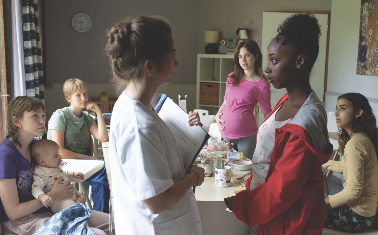 A still from Jeunes mères (Young mothers), showing a group of young women, some with children, sitting in a kitchen,