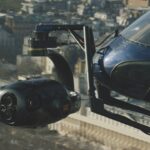 A helicopter with a camera attached to the front, flying over a city landscape