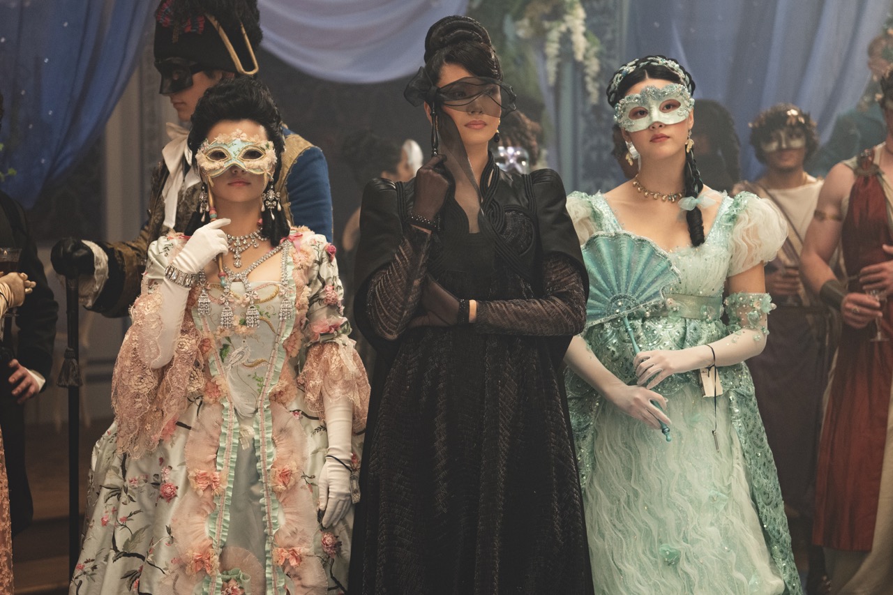 Three woman in period dress at a masquerade ball