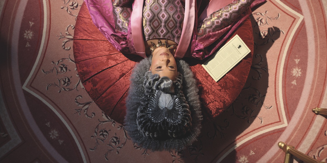 A queen with a large headpiece, laying on a red stall