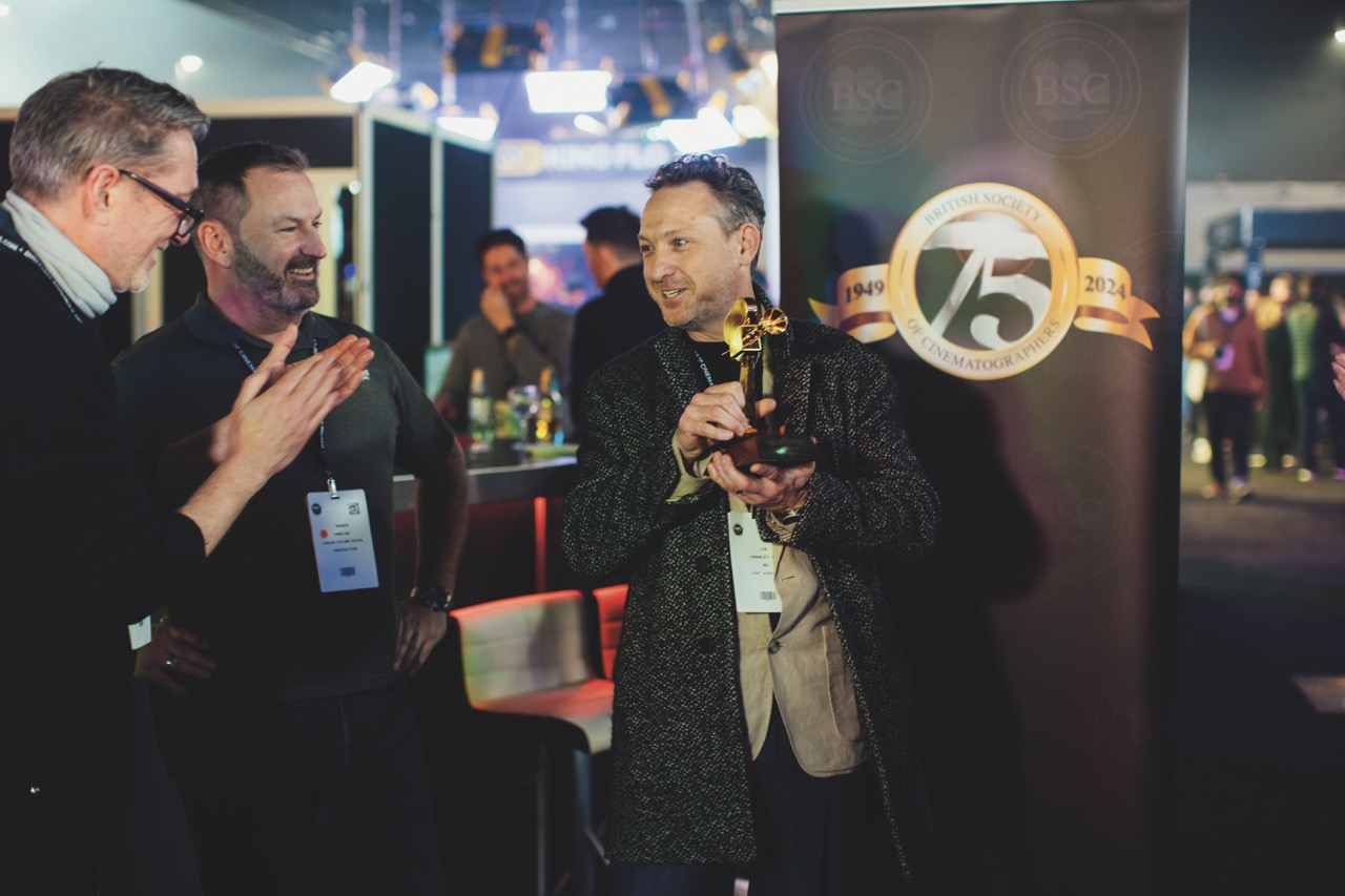 A person holding an award while other people congratulate on a busy conference floor