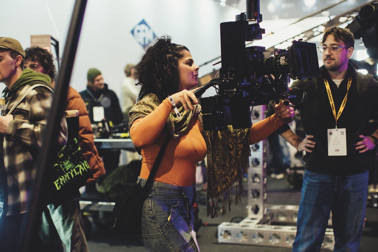 A woman in orange operating a professional camera at a conference