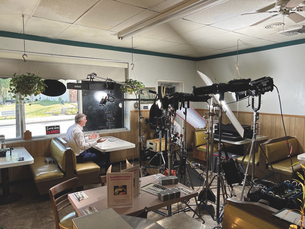 Established DOP Tim Cragg has worked on documentaries such as The Manhattan Alien Abduction (top) and Surviving Black Hawk Down (left) A diner packed with different lighting equipment and a man sitting at a table