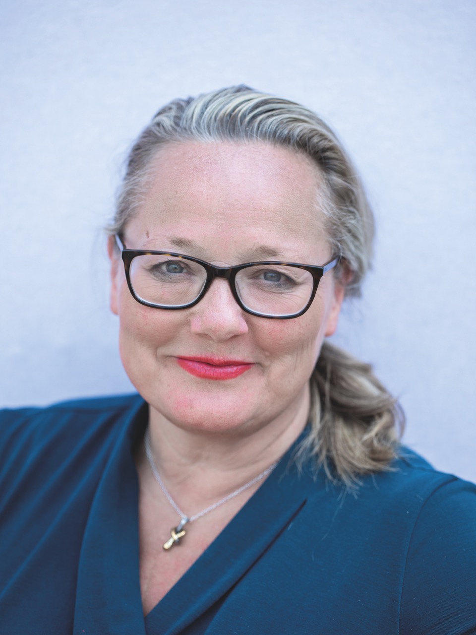 A smiling woman with glasses and a blue background