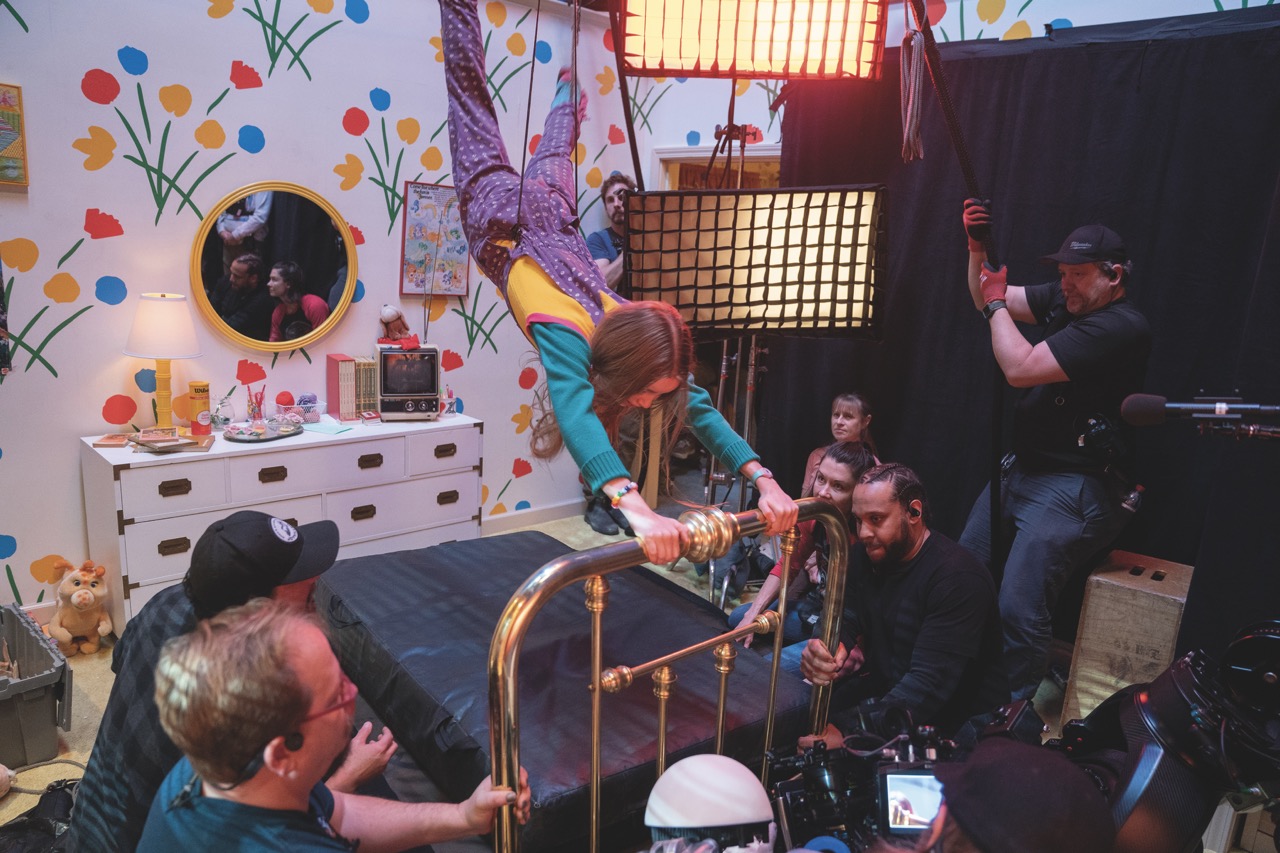 Holly’s abduction required intensive collaboration between departments; A young girl performing a stunt where she holds a bed railing, while a camera crew surrounds her