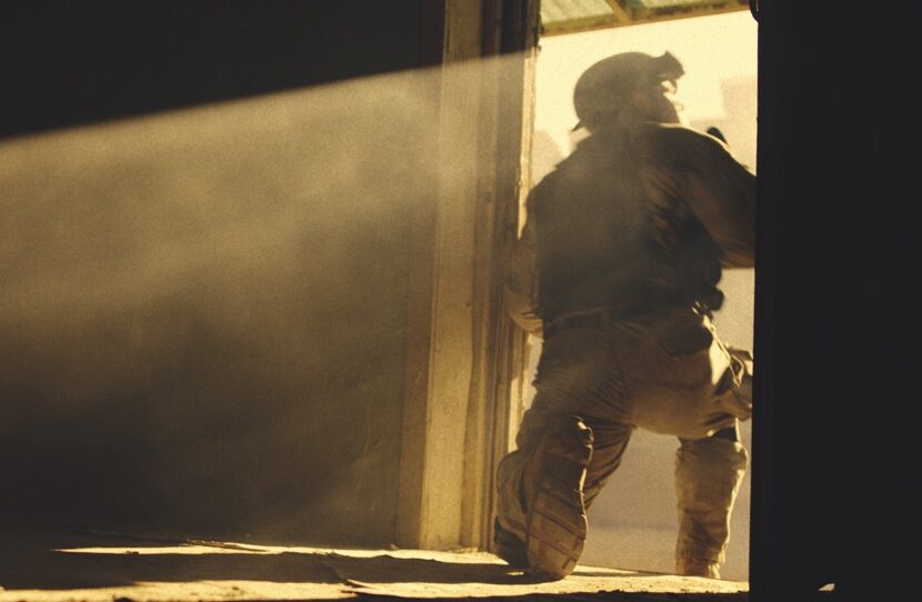 Established DOP Tim Cragg has worked on documentaries such as The Manhattan Alien Abduction (top) and Surviving Black Hawk Down (this image). Image Netflix A soldier kneeling in the doorway of a room with yellow light streaming in